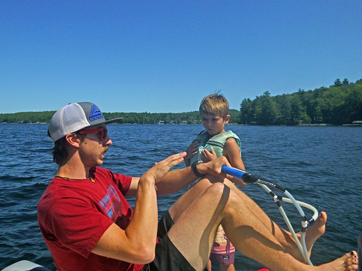 Camp counselor teaching camper how to wake board
